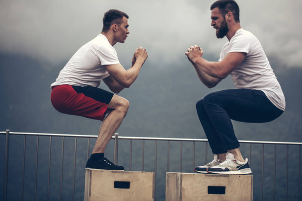Two male athletic friends doing box jump exercise outdoor - Fotografie, Obrázek