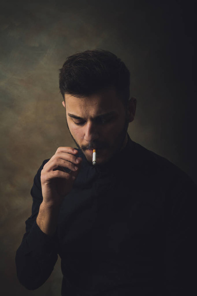 Portrait of young man smoking cigarette in art studio - Foto, Imagen