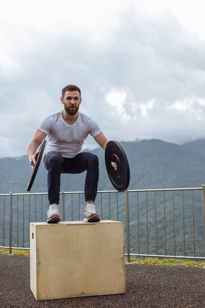 Strong male athlete doing box jumps with two plates outdoor on top of mountain. - Valokuva, kuva