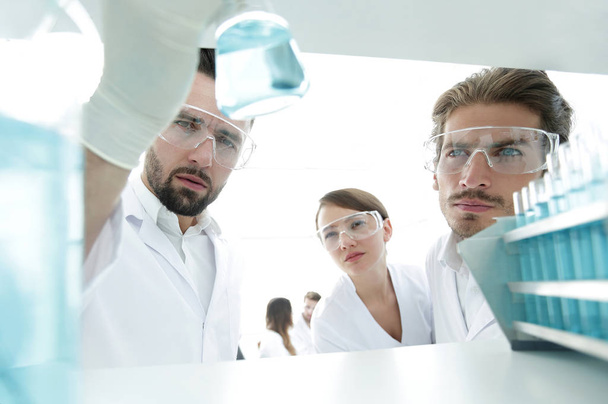 closeup. scientist and assistant studying the solution in the glass tube - Foto, afbeelding
