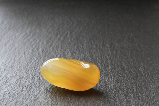 Une pierre d'agate de miel sur une planche de pierre noire
 - Photo, image