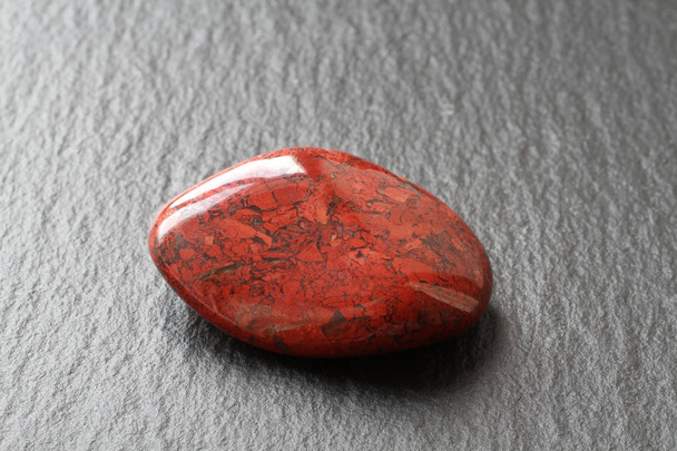 Rode jasper steen op een zwarte stenen bord - Foto, afbeelding