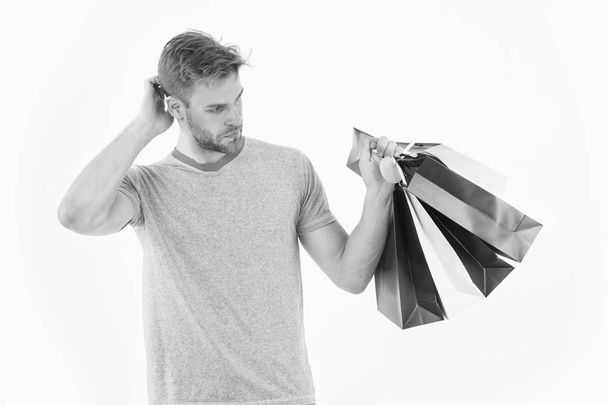 Shopaholic holding colorful paper bags. Hipster with stylish bristle isolated on white background. Man spending money on presents. Fashion addict with puzzled look. Christmas shopping, sales concept - Zdjęcie, obraz