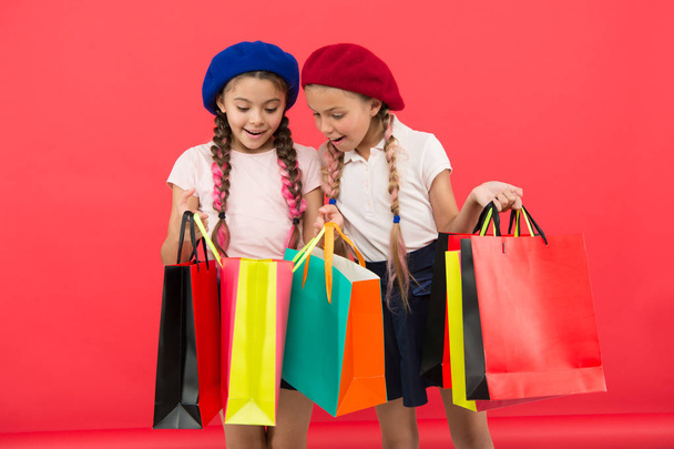 Shopaholic concept. Signs you are addicted to shopping. Kids cute schoolgirls hold bunch shopping bags. Children pupils satisfied by shopping red background. Obsessed with shopping and clothing malls - Фото, зображення