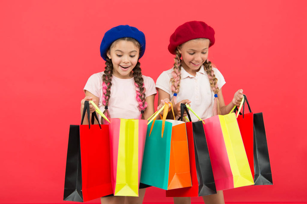 Children satisfied by shopping red background. Obsessed with shopping and clothing malls. Shopaholic concept. Shopping become fun with best friends. Kids cute schoolgirls hold bunch shopping bags - Photo, Image