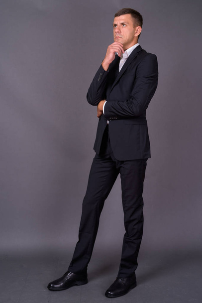 Handsome businessman with short hair against gray background - Fotó, kép