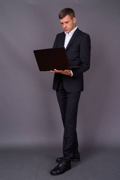 Handsome businessman with short hair against gray background - Zdjęcie, obraz