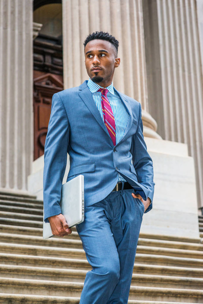 New York'ta, giyen karanlık gökyüzü mavi takım elbise, çalışma sakallı genç Afrikalı-Amerikalı işadamı merdivenden eski stil ofis binası üzerinden yürüyüş gömlek, mor kırmızı desenli kravat beyaz çizgili. - Fotoğraf, Görsel