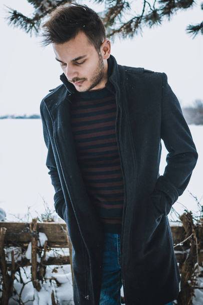 Young attractive man embracing the snow in winter. - Foto, afbeelding