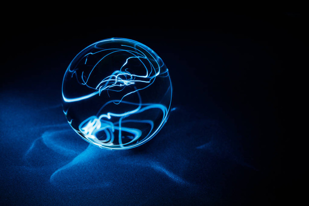 Transparent Crystal ball on black with blue light, close up. - Foto, afbeelding