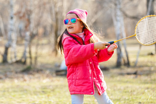 Little girl playing badminton on spring meadow - Valokuva, kuva