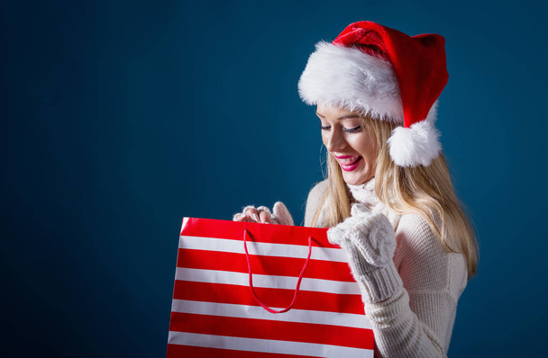 Young woman with santa hat holding a shopping bag - Foto, afbeelding