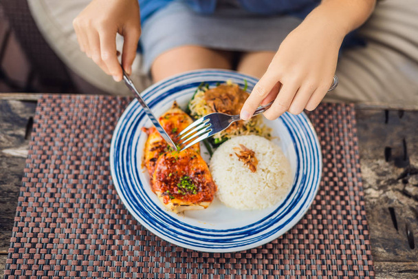 Обрізаний вид жінки, що їсть кальмари на грилі з рисом з столовими приборами
. - Фото, зображення