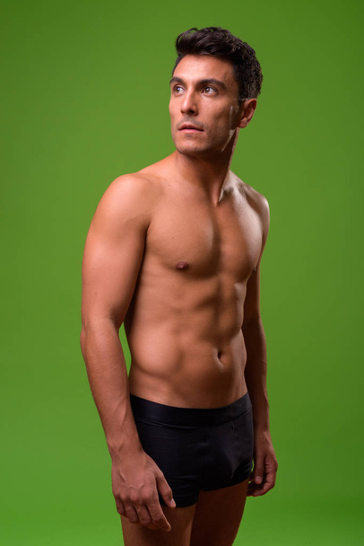 Joven hombre hispano guapo sin camisa sobre fondo verde
 - Foto, Imagen