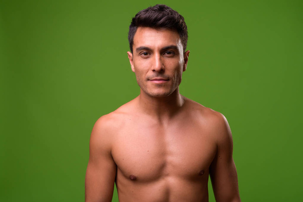 若いハンサムなヒスパニック男緑背景に上半身裸 - 写真・画像