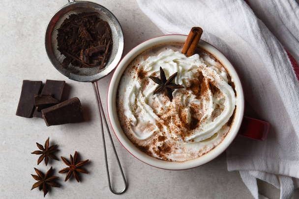 Top view of a large mug of hot cocoa topped with whipped cream and cinnamon and star anise. - Фото, изображение