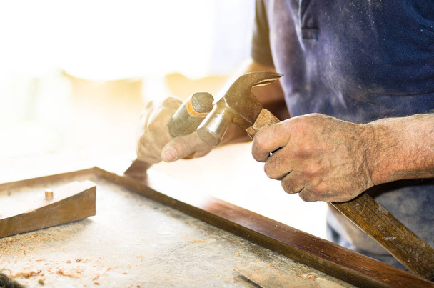 Primer plano de las manos de un carpintero que trabaja con un cincel y un martillo en un banco de trabajo de madera
 - Foto, imagen