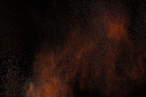 Orange powder explosion on black background. Flame cloud. Yellow dust explode. Freeze motion paint Holi. - Photo, image