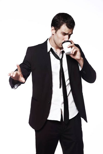 白い背景の上のコーヒー カップに黒のスーツで若い男になります手ジェスチャー。広告は、創造性。コーヒーを飲み. - 写真・画像