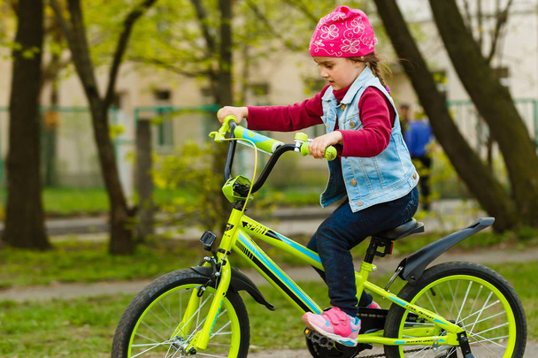 little girl riding bicycle in city park.  - Valokuva, kuva
