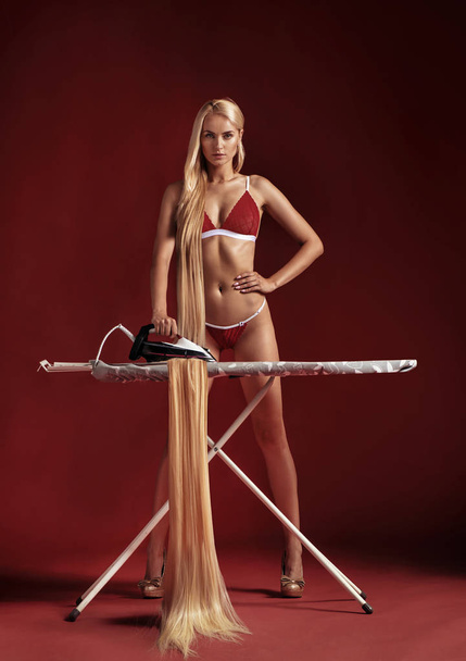 Conceptual picture of a blond woman ironing her hair - Foto, immagini