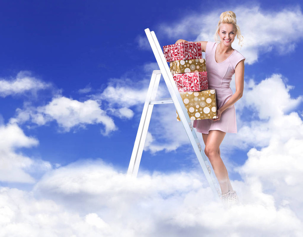 Cheerful woman holding a bunch of gifts - heaven concept - Фото, зображення