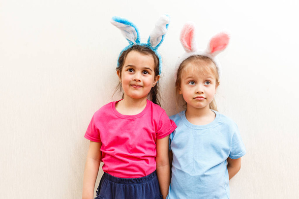 Duas garotinhas com orelhas de coelho isoladas no fundo branco
 - Foto, Imagem