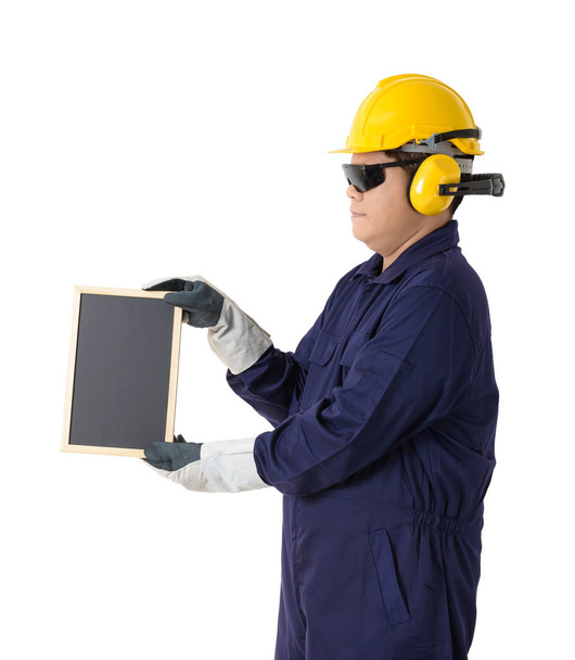 Portrait complet d'un travailleur en combinaison mécanique avec casque, cache-oreilles, gants de protection et lunettes de sécurité tenant le tableau isolé sur fond blanc chemin de coupe
 - Photo, image