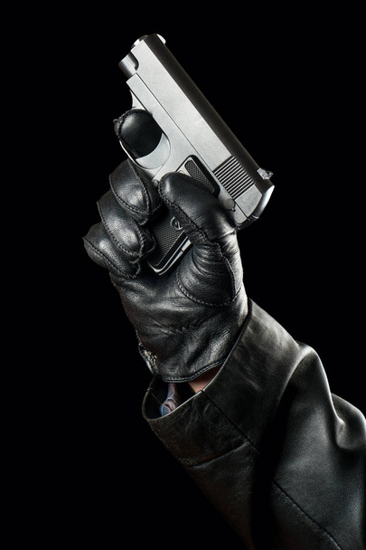 Fegyvert a kezében egy rabló kesztyűt visel egy fekete háttér - Fotó, kép