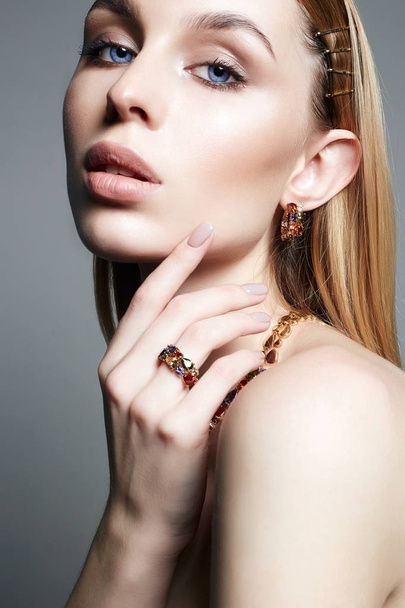 jonge blonde vrouw met make-up en sieraden accessoires. Gouden sieraden op mooi meisje - Foto, afbeelding