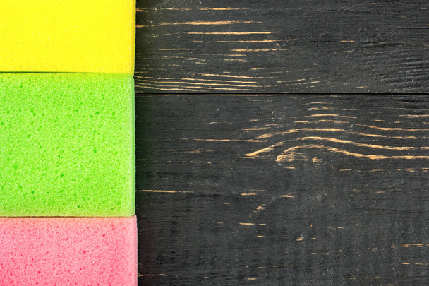 Τρία χρωματιστά σφουγγάρια για πλύσιμο πιάτων σε φόντο ξύλινη - Φωτογραφία, εικόνα