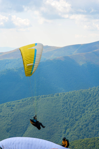 Paraglider fly over a mountain valley on a sunny summer day. Paragliding in the Carpathians in the summer. - Photo, Image