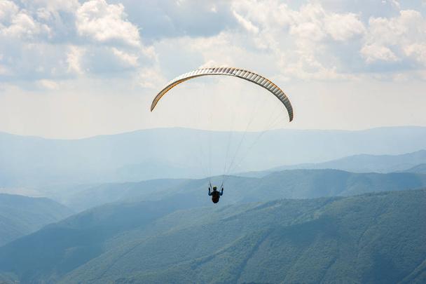 Parapente voar sobre um vale de montanha em um dia ensolarado de verão. Parapente nos Cárpatos no verão
. - Foto, Imagem