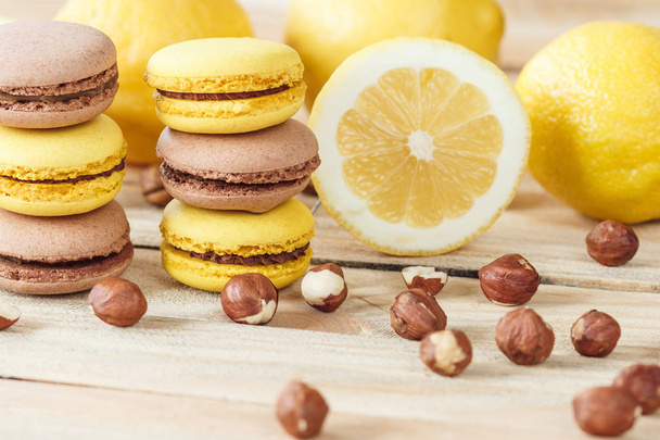 Yellow and brown french macarons with lemon and hazelnuts, soft focus background - Fotografie, Obrázek