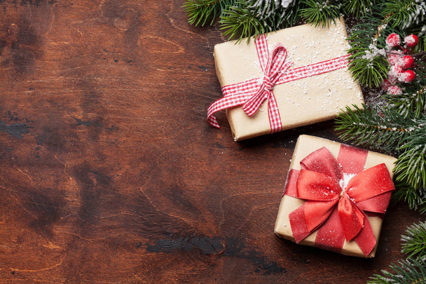 Рождественские подарочные коробки и ветки елки, покрытые снегом на деревянном фоне. Вид сверху xmas backdrop с пространством для поздравлений
 - Фото, изображение