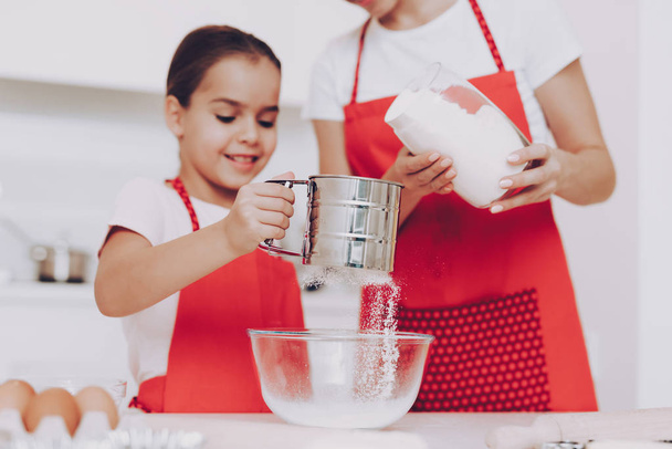 Young Girl Preparation Sugar for Sweet Biscuit and Sweet Pancakes. Mother Help Yung Girl with Preparation. Happy Girl with Mother. Young Girl Bake a Cake with Mother at Home. Kitchen for Mom and Girl. - 写真・画像