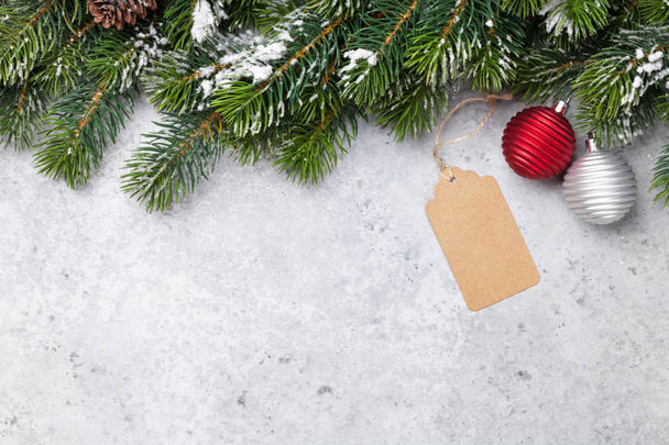 Kerst fir tree branch vallende sneeuw en bauble decor op stenen achtergrond. Xmas decor voor uw wenskaart met ruimte voor tekst - Foto, afbeelding