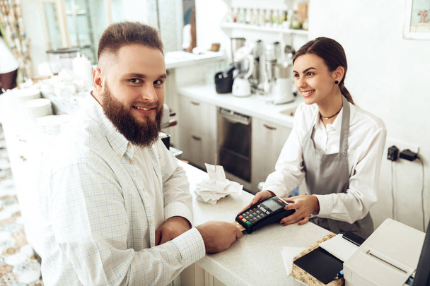 Cheerful cashier using digital device for payment - Photo, image