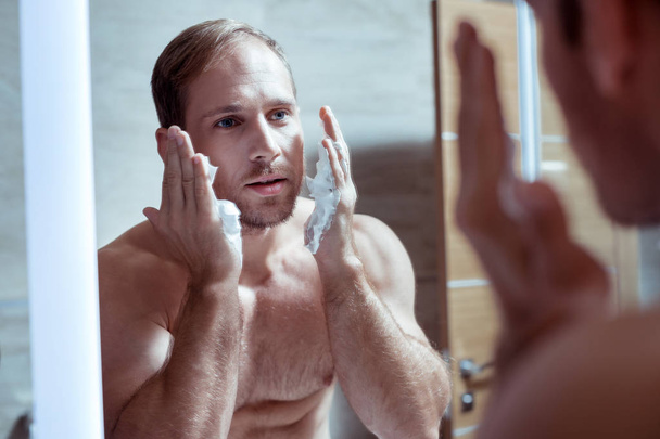 Handsome good-looking blue-eyed man shaving his face in the morning - Photo, Image