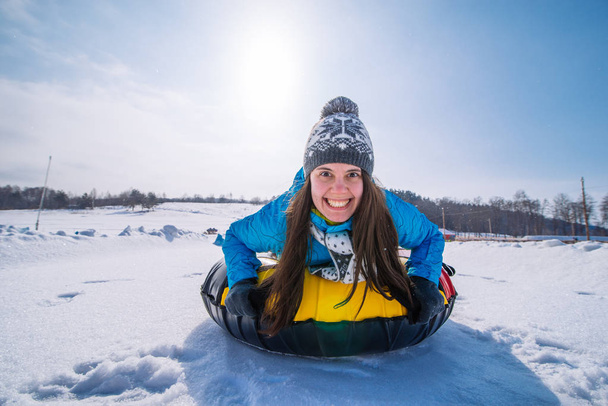 junge lächelnde Frau hält sich für Schlitten. Snow Tubing. Winteraktivitätskonzept - Foto, Bild