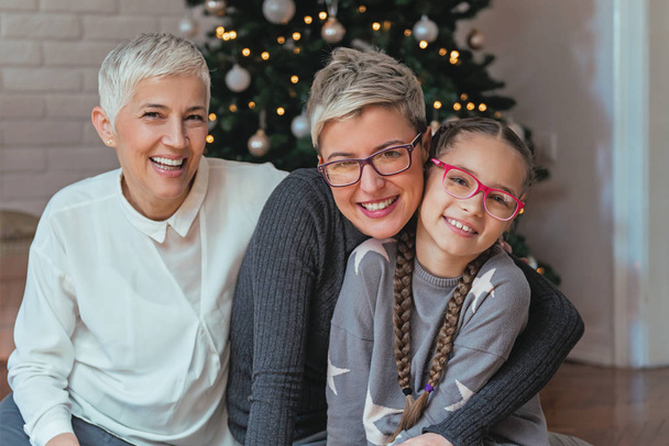 Família reunida em torno de uma árvore de Natal, gerações femininas
 - Foto, Imagem
