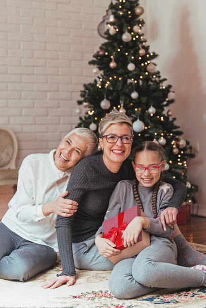 Family gathered around a Christmas tree, female generations - Фото, изображение