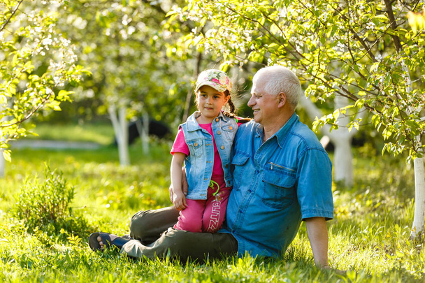 Grand-père avec petite-fille au repos dans le jardin de printemps
 - Photo, image