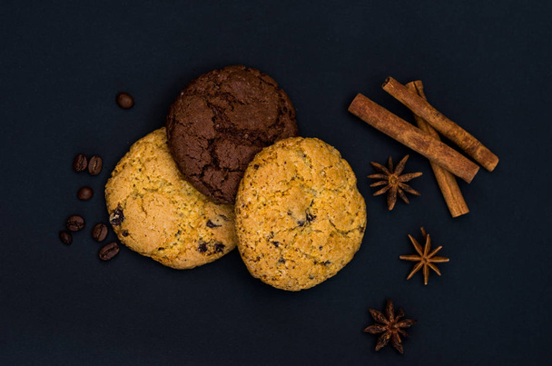 Chocolate and milk biscuits with spices and coffee beans. Top view. Lie flat on a black background. - Foto, Imagen