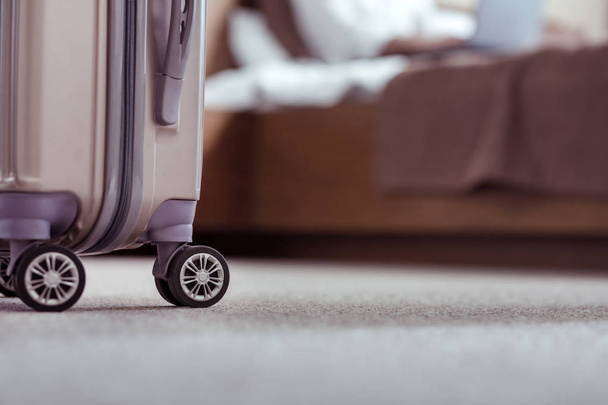 Dark grey luggage standing near big double bed in hotel room - Zdjęcie, obraz