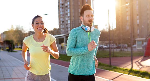 Mladí fitness pár běží společně v městské oblasti - Fotografie, Obrázek