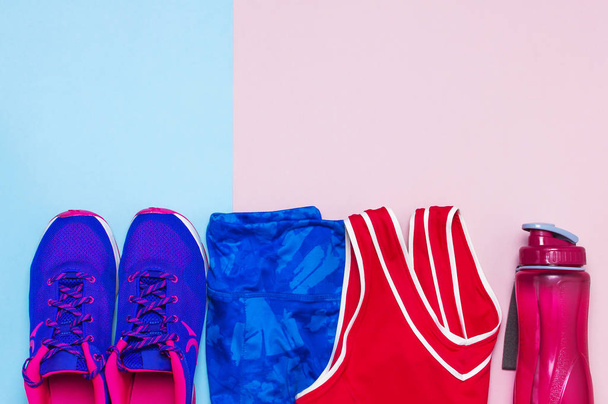 Sneakers femminili ultra viola, top rosa leggings sportivi blu e bottiglia d'acqua su sfondo rosa pastello flat lay top view con spazio copia. Scarpe sportive, concetto di fitness di stile di vita sano
. - Foto, immagini