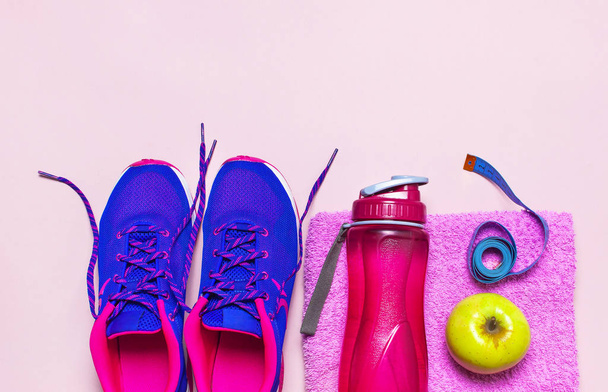 ウルトラ バイオレット ピンク女性スニーカー、水のボトル、ピンクのタオルとフィットネスの概念、パステル ピンク背景の平面の上のリンゴには、平面図が横たわっていた。スポーツ シューズ、フィットネス健康 lifestile の概念. - 写真・画像