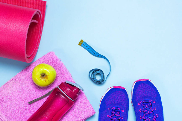 Fitness concept with Ultra violet pink female sneakers, water bottle, towel, apple on pastel blue background flat lay top view. Sports shoes, fitness concept of healthy lifestile. - Photo, Image