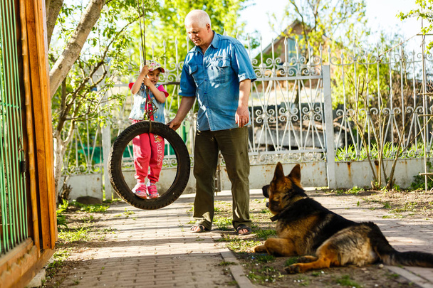 Děda s vnučkou a pes odpočívá v jarní zahradě - Fotografie, Obrázek